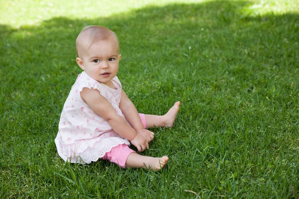 Cute baby sitting on grass at park — Stock Photo, Image