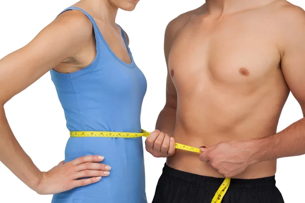 Sección media de un hombre en forma que mide la cintura de las mujeres — Foto de Stock