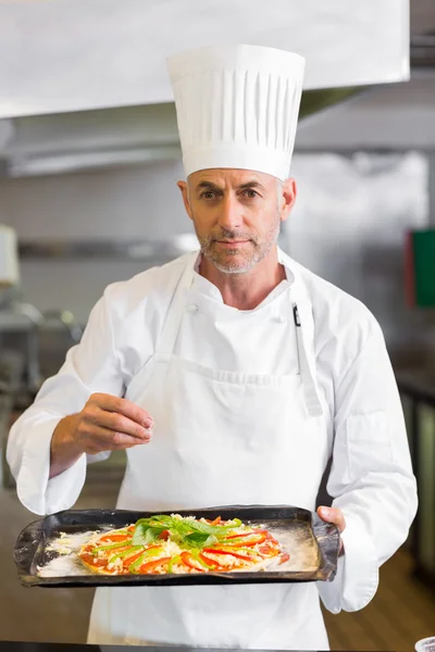Selbstbewusster Koch hält gekochtes Essen in der Küche — Stockfoto