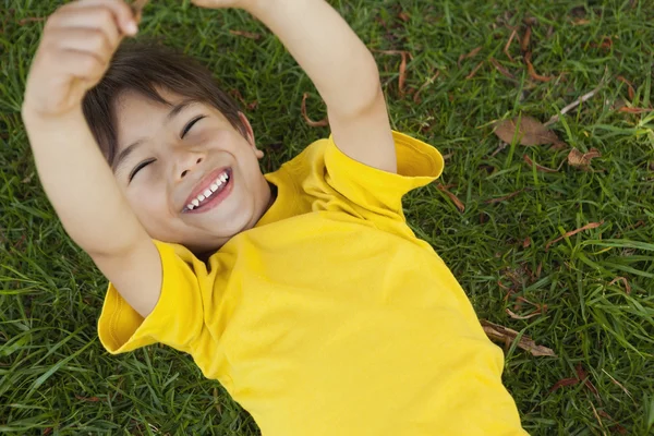 Jeune garçon couché sur l'herbe au parc — Photo