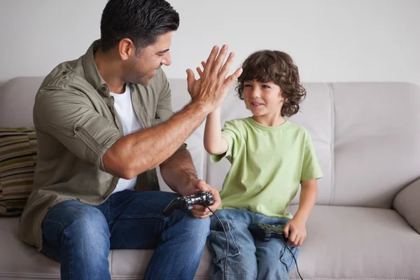 Vader en zoon spelen van videospellen in woonkamer — Stockfoto