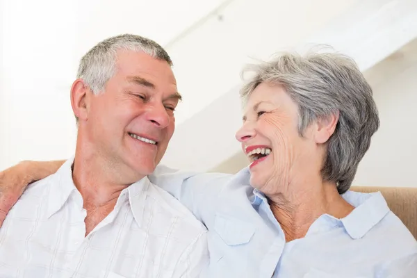 Пенсионеры сидят на диване и улыбаются друг другу. — стоковое фото