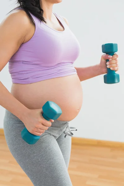 Morena grávida segurando halteres — Fotografia de Stock