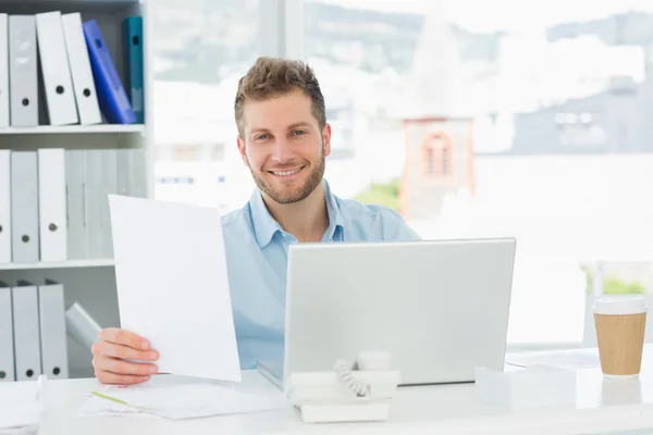 Bonito homem trabalhando em sua mesa no laptop — Fotografia de Stock