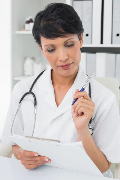 Concentrated female doctor writing on clipboard — Stock Photo, Image