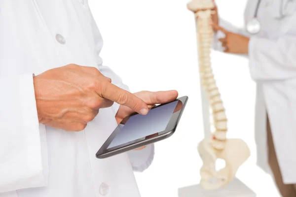 Mid section of doctors with digital table and skeleton model — Stock Photo, Image