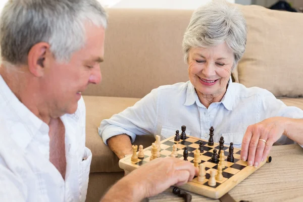 Старшая пара сидит на полу и играет в шахматы — стоковое фото
