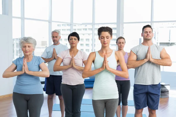 People with eyes closed and joined hands at fitness studio — Stock Photo, Image