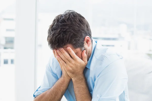 Man with head in hands sitting on the couch — Stock Photo, Image