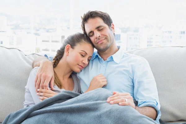 Fröhliches Paar entspannt sich auf dem Sofa unter einer Decke — Stockfoto