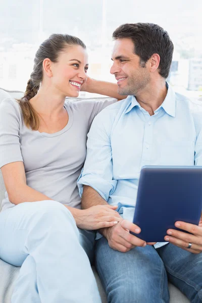 Casal bonito sentado no sofá usando tablet pc — Fotografia de Stock