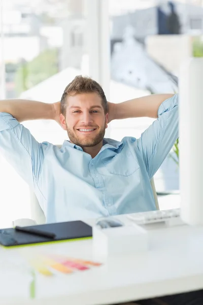 Bonito designer relaxante em sua mesa sorrindo para a câmera — Fotografia de Stock