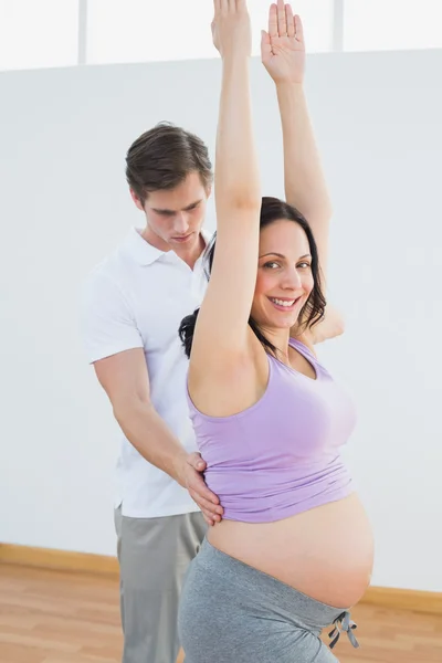 Mujer embarazada feliz haciendo yoga con un entrenador personal —  Fotos de Stock