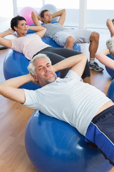 Smiling people stretching on exercise balls in gym — Stock Photo, Image