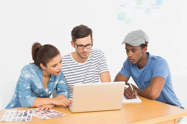 Tres jóvenes artistas concentrados trabajando en el ordenador portátil — Foto de Stock