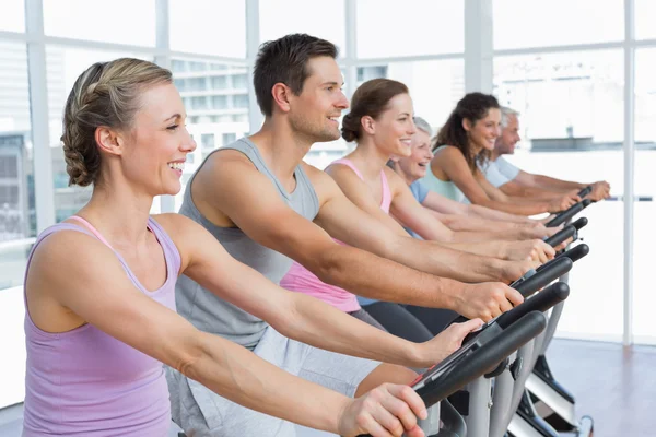 Gente feliz haciendo ejercicio en la clase de spinning —  Fotos de Stock