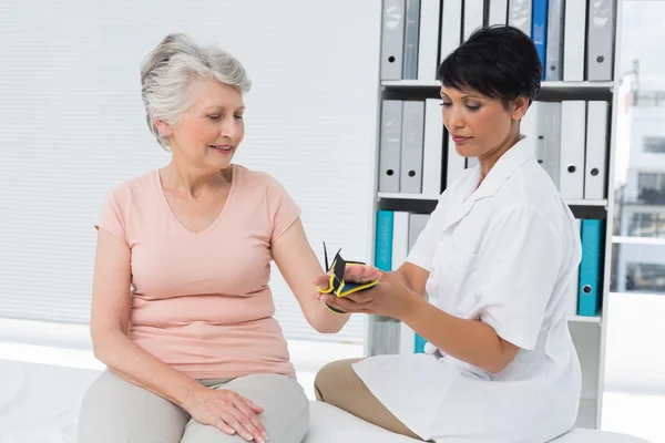 Doctor fixing wrist brace on senior patients hand — Stock Photo, Image