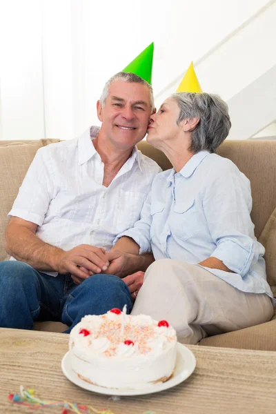 Casal sênior sentado no sofá comemorando um aniversário — Fotografia de Stock