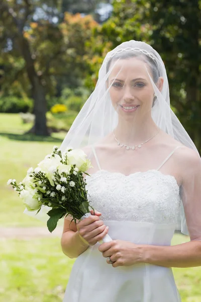 Braut mit Blumenstrauß trägt Schleier — Stockfoto