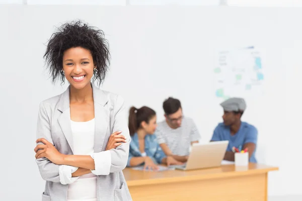 Artiste féminine occasionnelle avec des collègues en arrière-plan au bureau — Photo