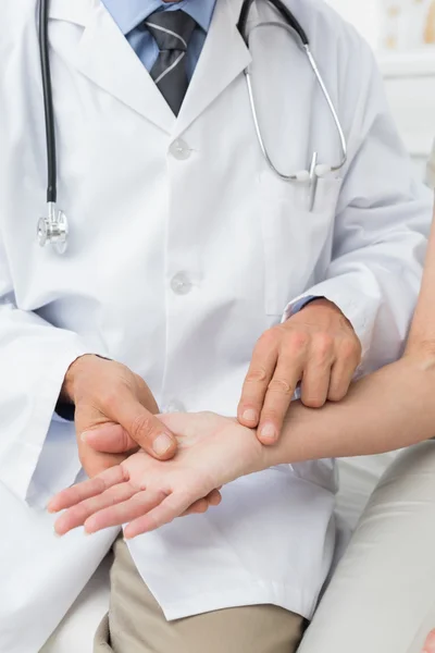 Mid section of a doctor taking a patients pulse — Stock Photo, Image