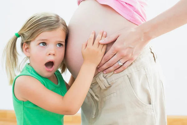 母親の妊娠中の腹を聴いている女の子 — ストック写真