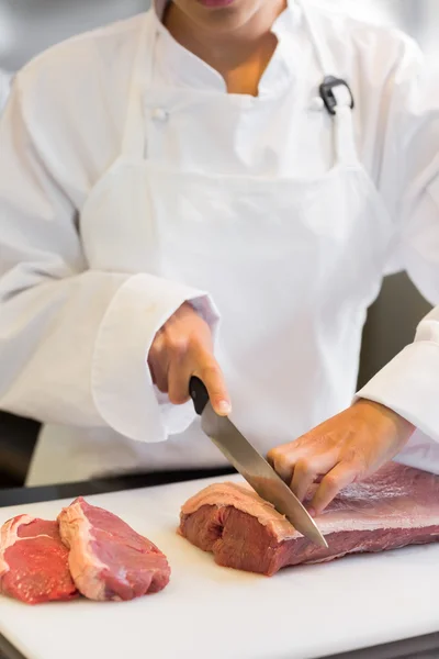 Hands cutting meat in kitchen — Stock Photo, Image