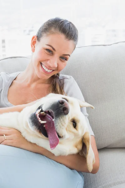 Szczęśliwa kobieta pieszczoty jej żółty labrador na kanapie — Zdjęcie stockowe