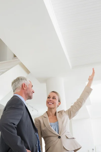 Sorrindo agente imobiliário mostrando teto para potencial comprador — Fotografia de Stock