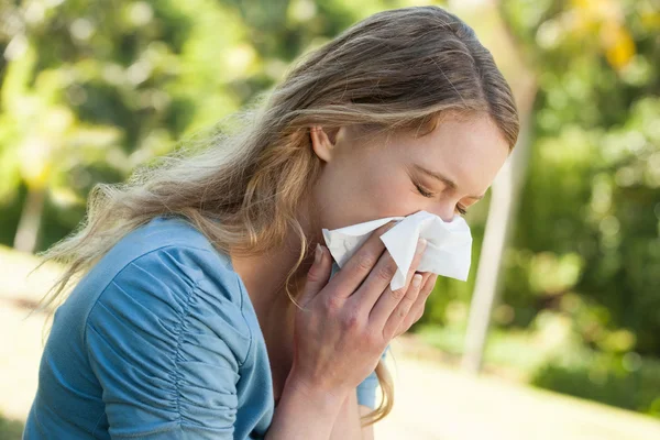 Woman blowing nose with tissue paper at park — Stock Photo, Image