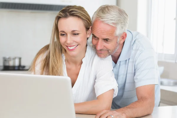 Happy couple using laptop together at the counter — Stock Photo, Image