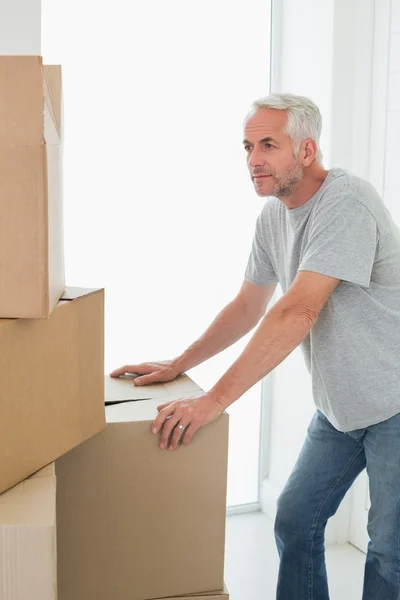 Hombre reflexivo mirando cajas móviles de cartón —  Fotos de Stock