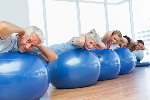 Sportieve mensen uitrekken op oefening ballen in de sportschool — Stockfoto