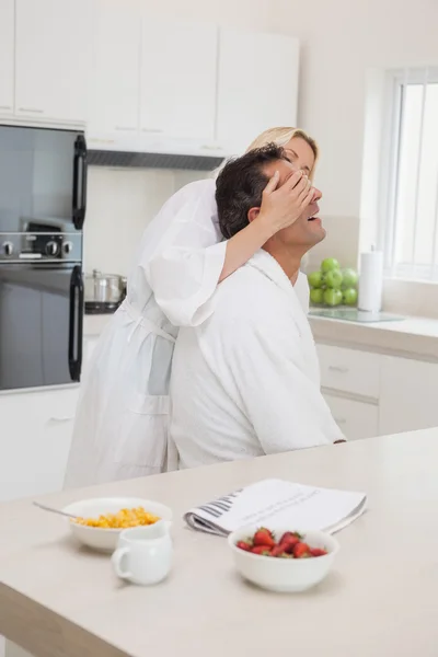 Woman covering man's eyes at breakfast table — Stock Photo, Image