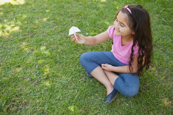 Gelukkig meisje spelen met een papieren vliegtuig in het park — Zdjęcie stockowe