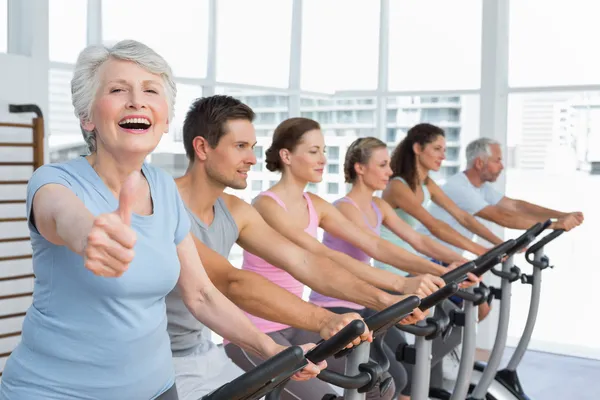 Woman gesturing thumbs up with class at spinning class — Stock Photo, Image