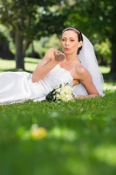 Bride blowing a kiss in park — Stock Photo, Image