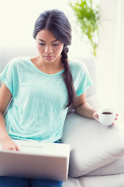 Flicka sitter på en soffa med laptop — Stockfoto