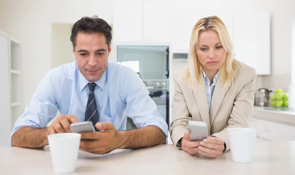 Couple text messaging in the kitchen — Stock Photo, Image