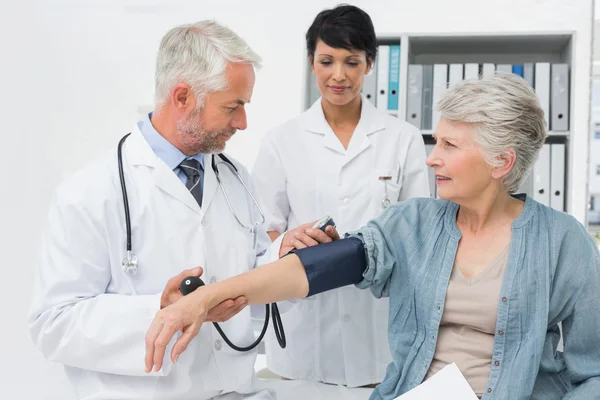 Dokter die de bloeddruk van een oudere patiënt meet — Stockfoto