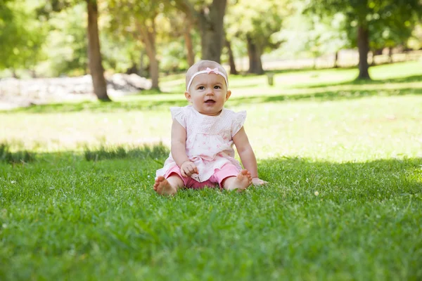 Happy cute baby sitting on grass at park — Stock Photo, Image