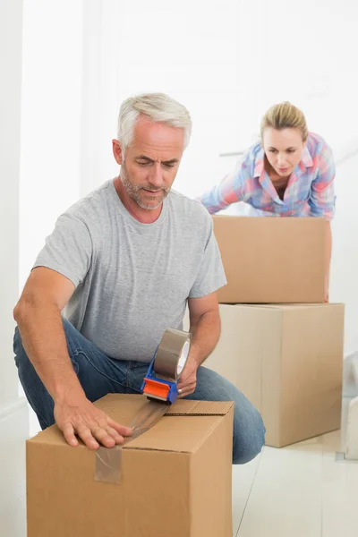 Happy couple sealing cardboard moving boxes — Stock Photo, Image