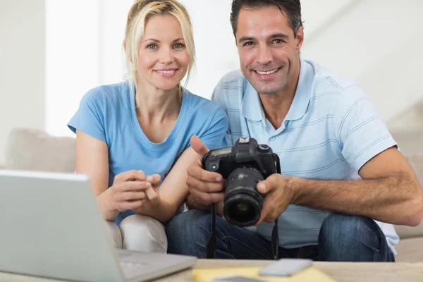 Casal com câmera e laptop no sofá — Fotografia de Stock