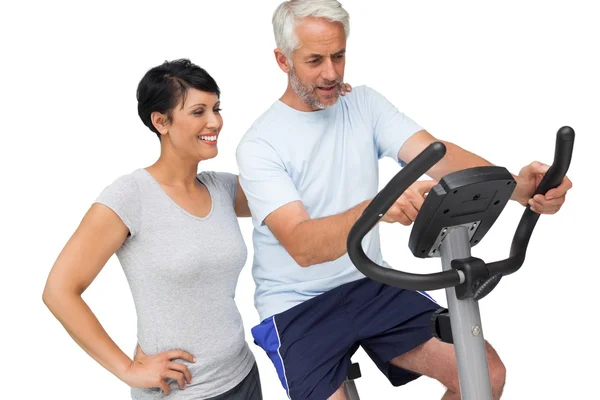 Happy woman looking at mature man on stationary bike — Stock Photo, Image