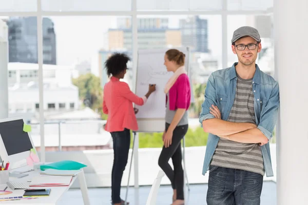 Artiste masculin occasionnel avec des collègues en arrière-plan au bureau — Photo