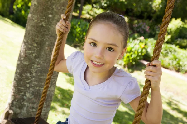 快乐的小女孩坐在秋千上，在公园 — 图库照片