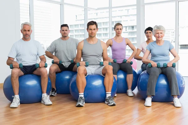 Aula de fitness com halteres sentados em bolas de exercício no ginásio — Fotografia de Stock