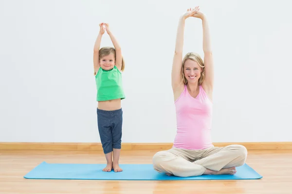 Pregnant mother and daughter doing yoga — Stock Photo, Image