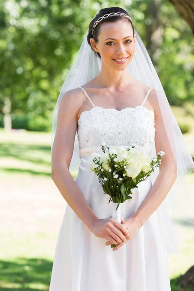 Bride holding bouquet in park — Stock Photo, Image
