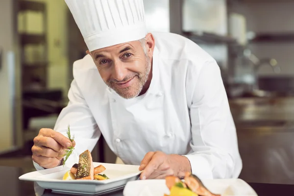 Sorrindo chef masculino guarnição de alimentos na cozinha — Fotografia de Stock